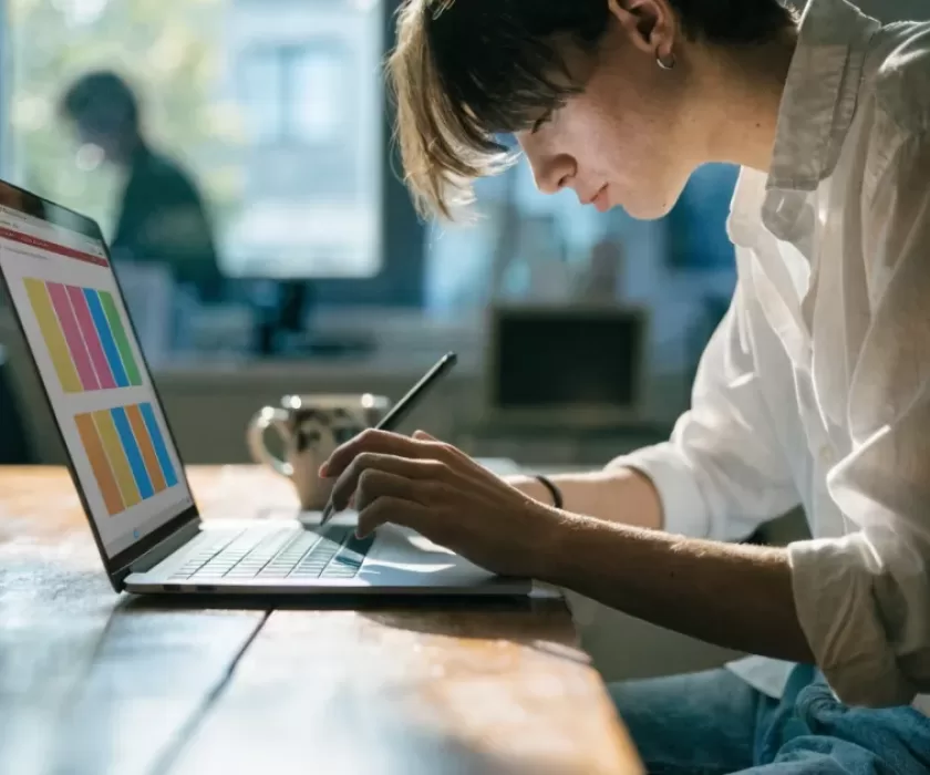 Canva Code 2.0 AI website builder shown as a person editing a colorful webpage design on a laptop